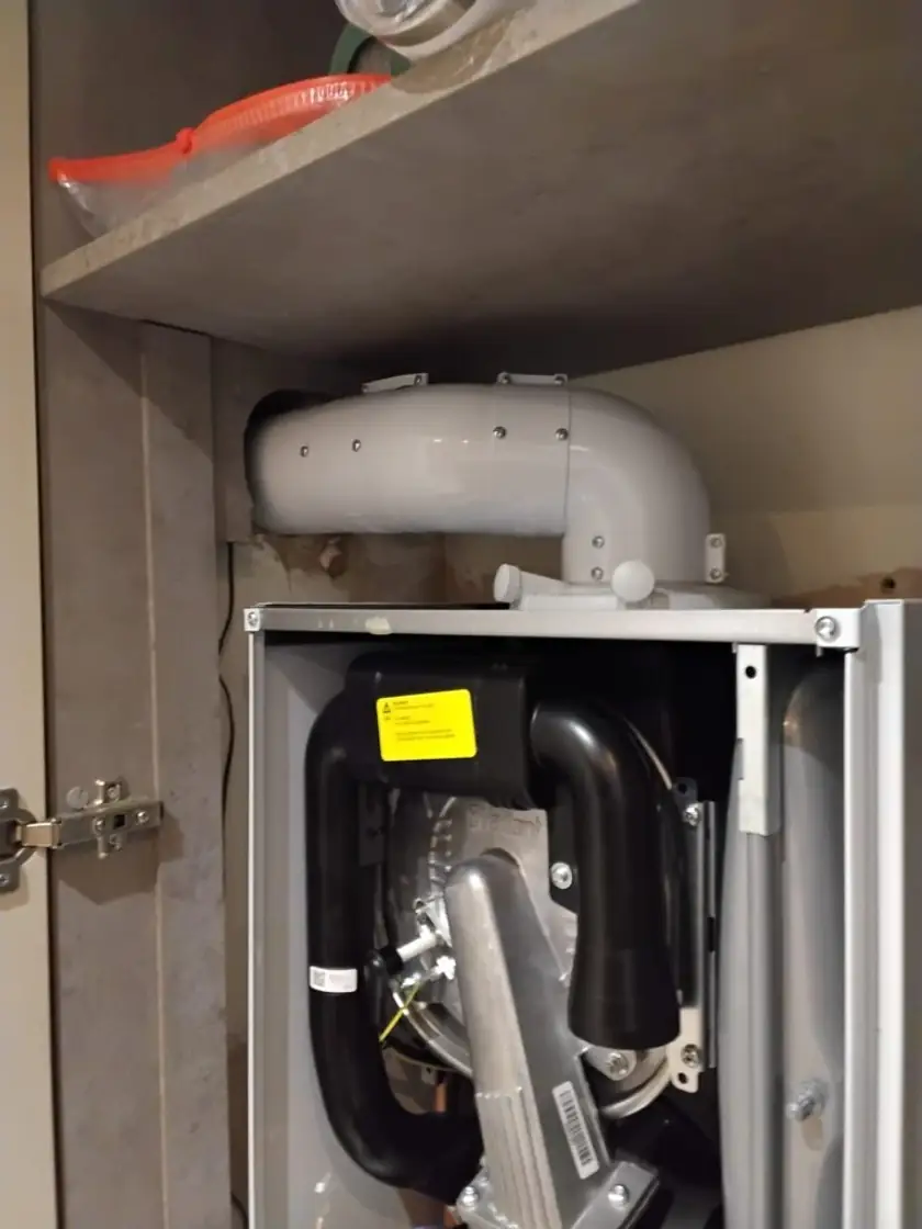 Wall-hung boiler with casing removed during install, flue connected through the wall